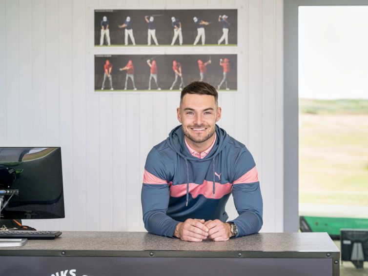 Golf teaching pro Fraser Clark leaning on a desk